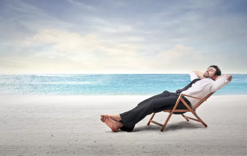 Mann entspannt sich auf einem Liegestuhl am Strand mit Blick auf das Meer