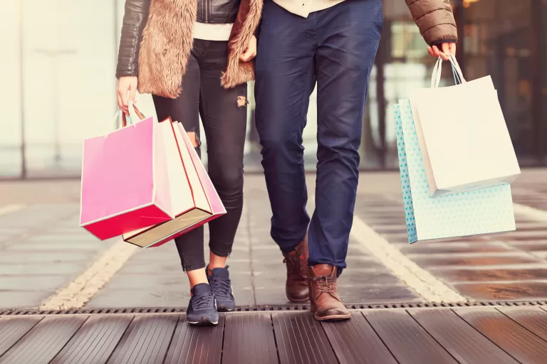 Mann und Frau Hand in Hand mit vielen Einkaufssackerln.