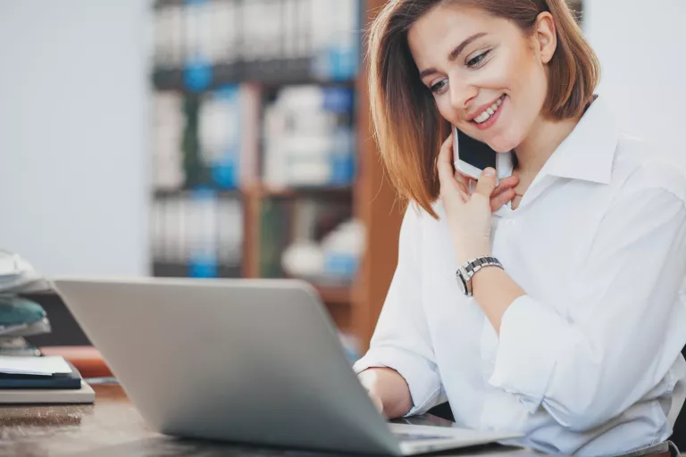 Frau sitzt am Laptop und telefoniert