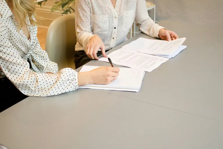 Zwei Damen besprechen Dokumente an einem Schreibtisch