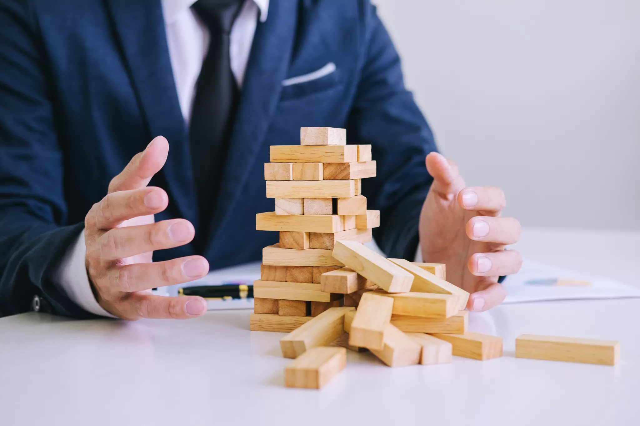 Mann im Anzug entsetzt über einstürzenden Jenga-Turm