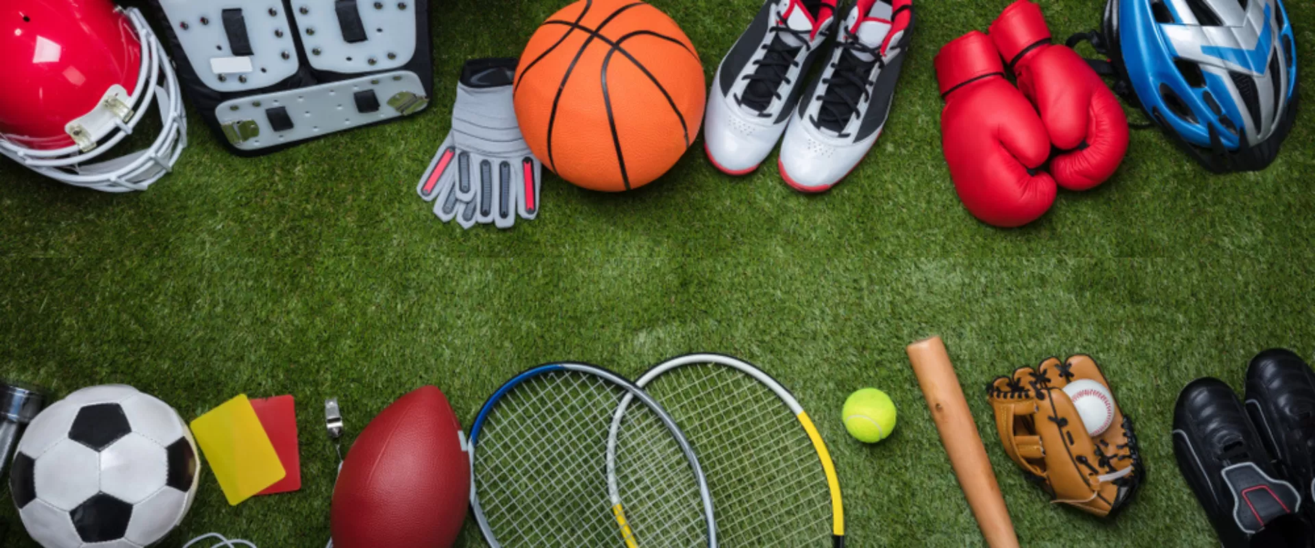 Unterschiedliche Sportartikel auf Grass. Zum Beispiel: Boxhandschuhe, Helm, Baseballschläger, Tennisball, Fußball, Handschuhe und mehr.